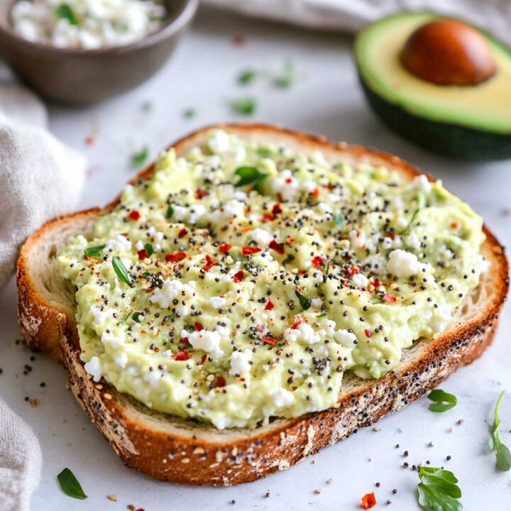 Avocado cottage cheese toast on a white marble surface.