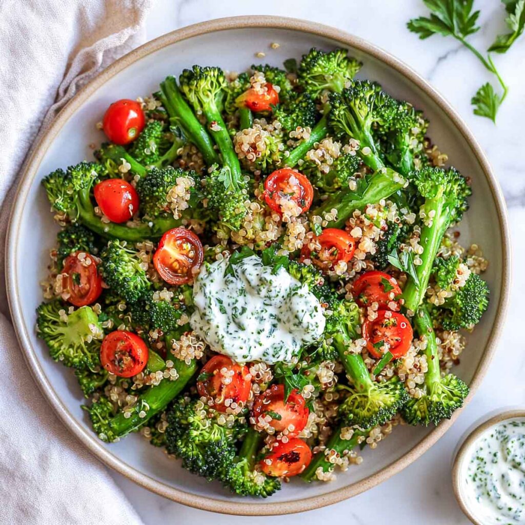 A bowl of brococolini and quinoa salad topped with a yogurt dressing.