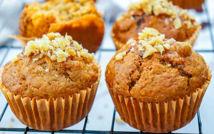 Four carrot cake muffins sitting on a wire rack.