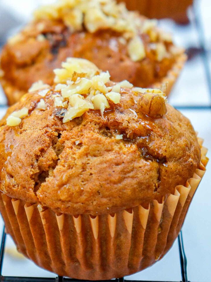 Carrot cake muffins topped with chopped walnuts.