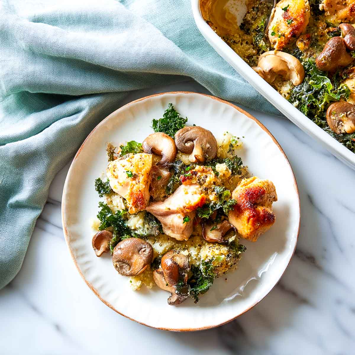 Chicken mushroom casserole served on a white plate with the baked dish in the background.