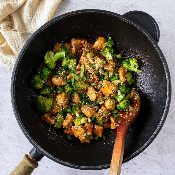 Honey garlic chicken and broccoli cooked in a black wok.