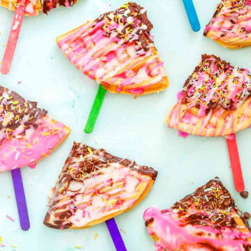 Close-up of a pink and chocolate-drizzled waffle pop with rainbow sprinkles, perfect for kids’ parties or fun desserts.