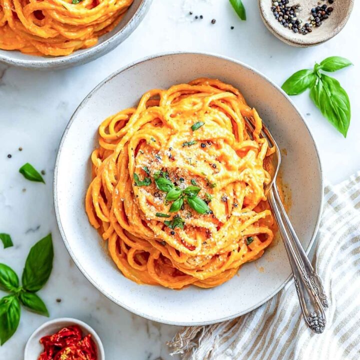 Spaghetti in an orange roasted red pepper sauce, topped with basil and cheese.