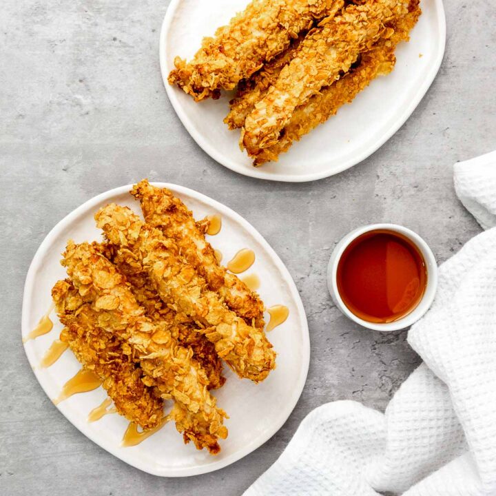 Two plates of crispy cornflake chicken drizzled with hot honey.