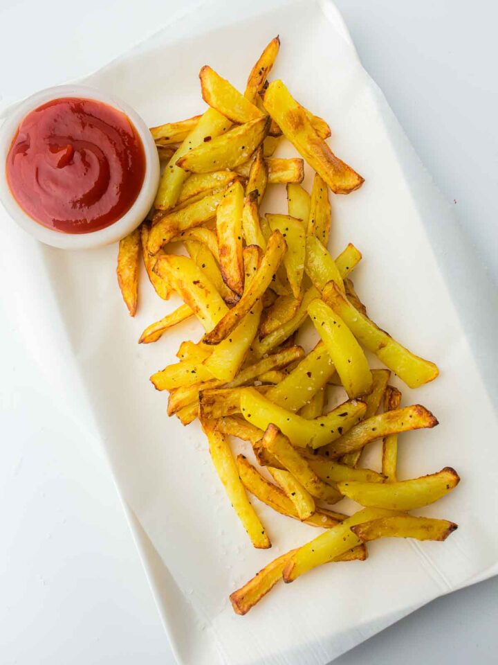 Air fryer French fries served on a rectangular plate with ketchup.