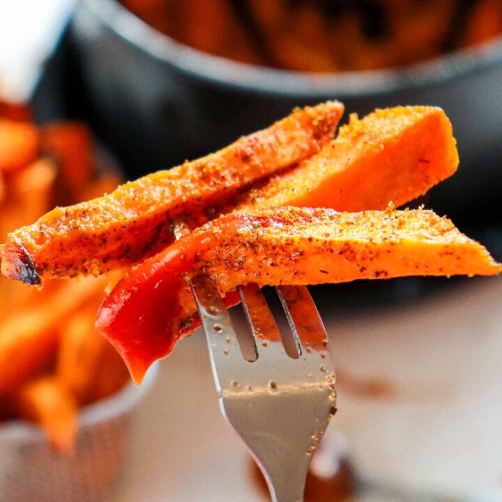 Close up of sweet potato fries on a fork to show the texture.