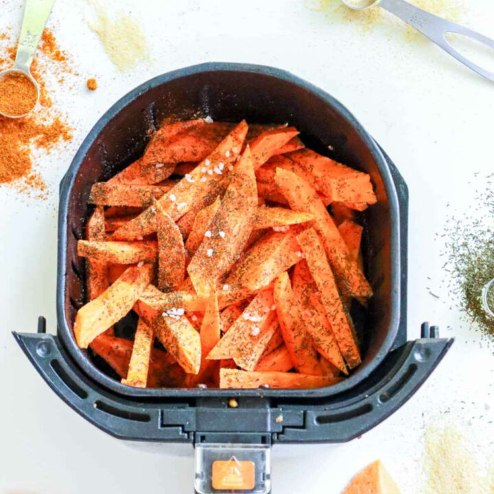 Uncooked sweet potato fries in air fryer basket.