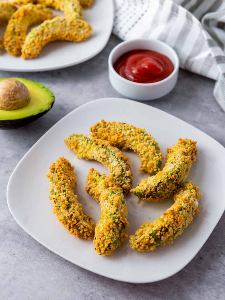 Crispy air fryer avocado fries served on a white plate with ketchup.