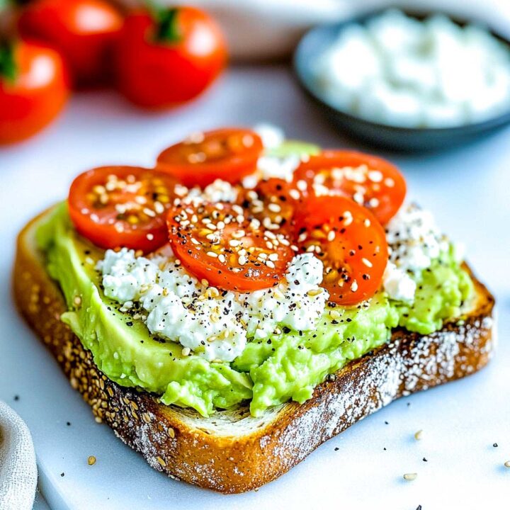 Avocado toast on whole-grain bread topped with cottage cheese, sliced cherry tomatoes, and everything bagel seasoning.