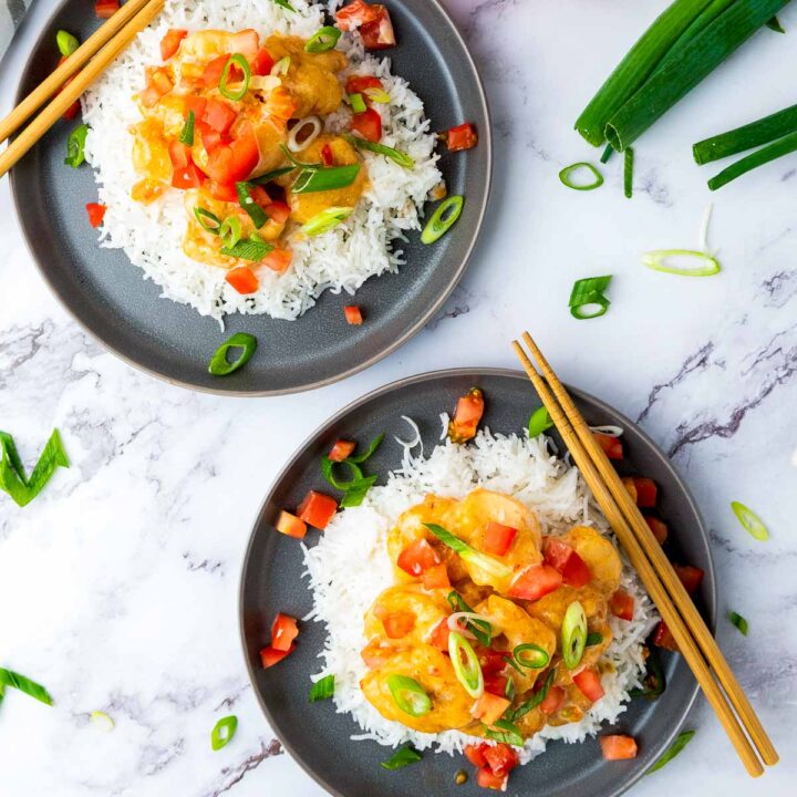 Two plates on bang bang shrimp on a marble surface.
