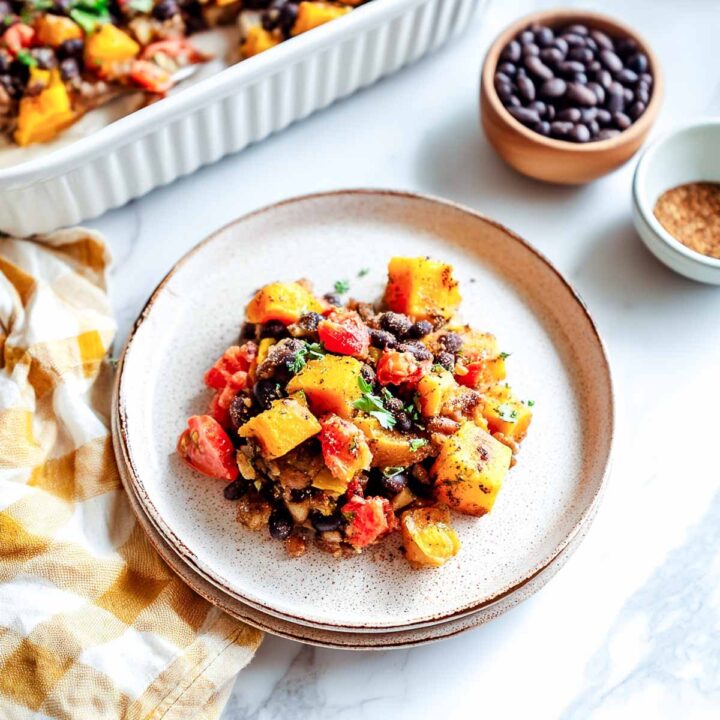 Butternut squash, black bean, and tomato mixture served on a speckled plate.