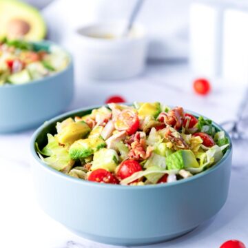 Side view of a bowl of chopped chicken salad placed on a marble surface.