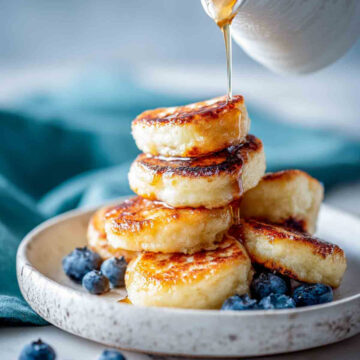 Close up of mini cottage cheese pancake bites on plate with blueberries and syrup.