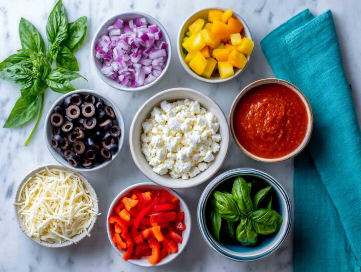 Prepped cottage cheese pizza bowl ingredients arranged on marble with turquoise napkin.