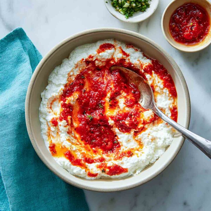 Cottage cheese and marinara being mixed in a bowl with a spoon.