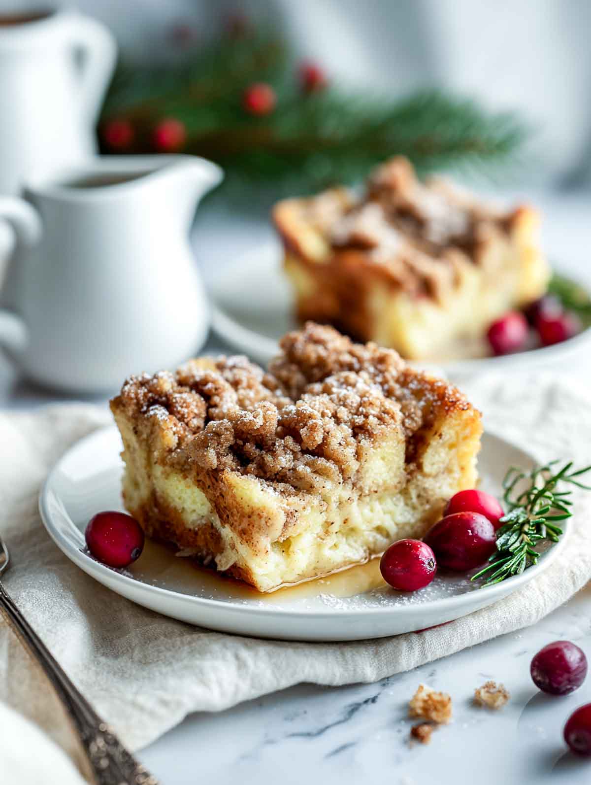 Slice of eggnog French toast casserole served with rosemary and cranberries.