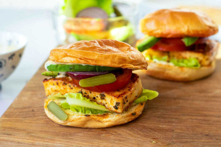 Two assembled halloumi burgers on a wooden board.
