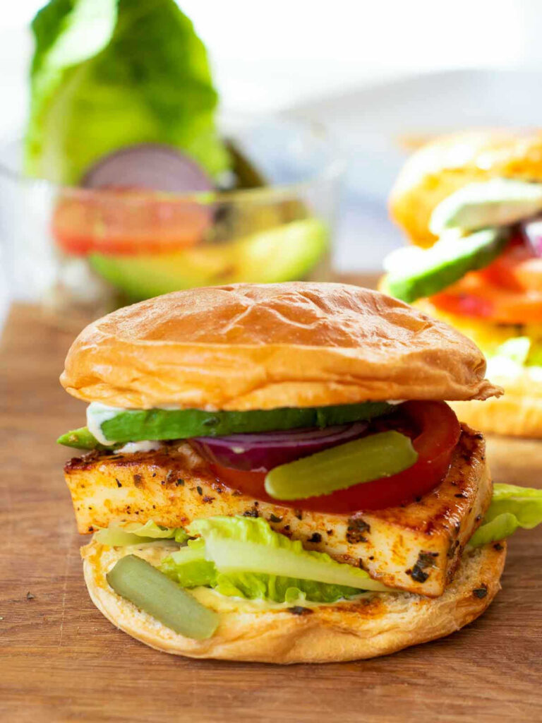 Close up of assembled halloumi burger on a wooden board.