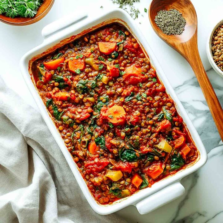 Lentil and vegetable casserole with carrots, spinach, and tomatoes served in a white baking dish.
