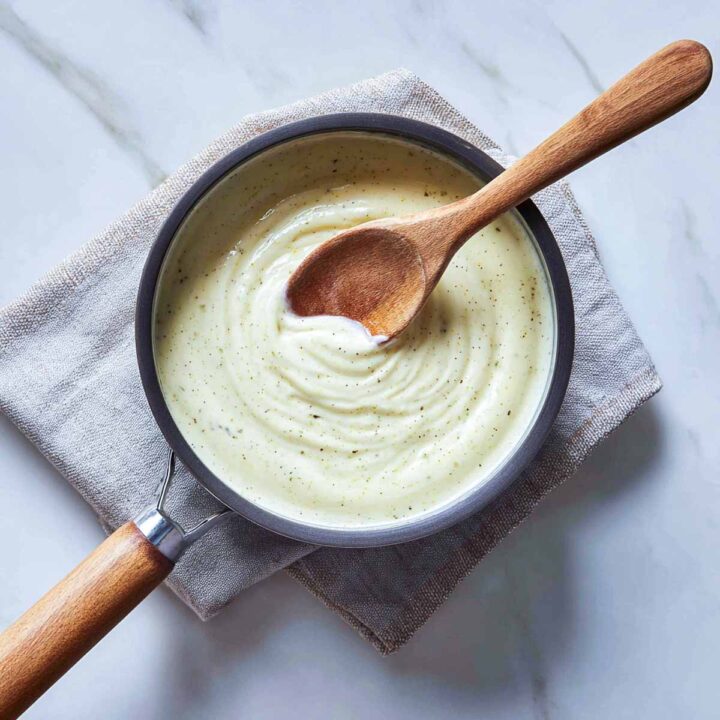 Creamy garlic sauce stirred in a saucepan for the casserole base.