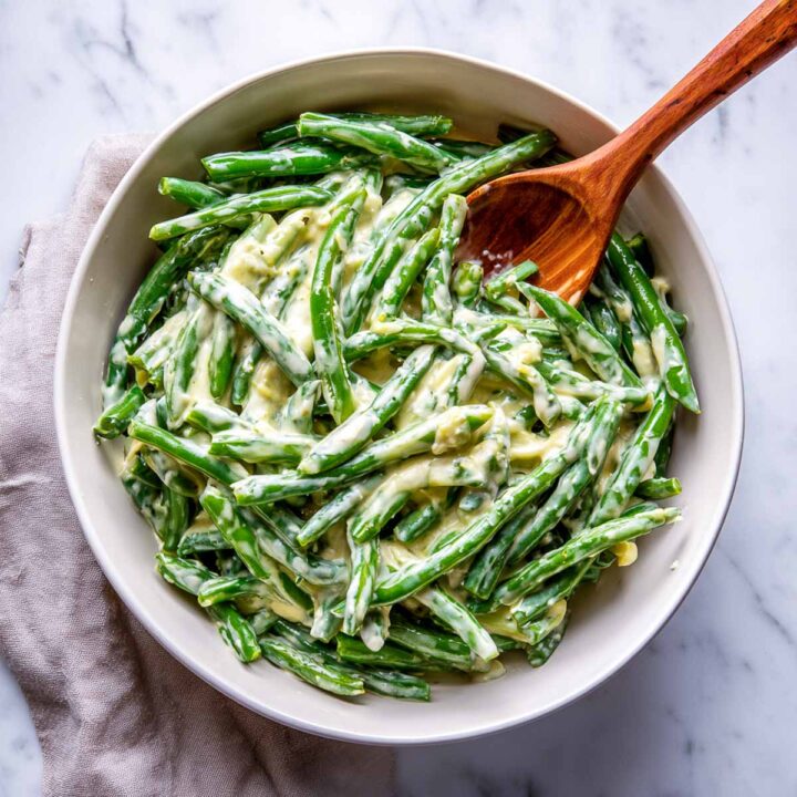 Green beans mixed with creamy garlic sauce in a bowl before assembling.