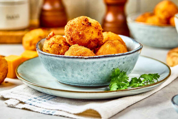 Side view of a bowl of crisp mac and cheese bites.