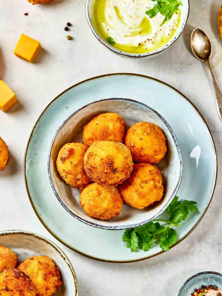 Top view of mac and cheese bites with dipping sauce in the background.
