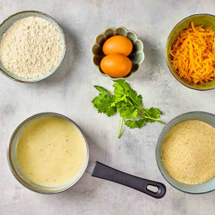 White sauce in a small small saucepan placed on a grey surface.
