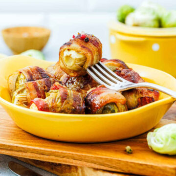 Side view of crispy bacon-wrapped Brussels sprouts in a fork.