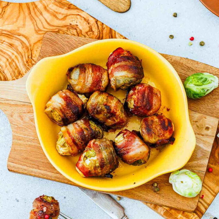 Crispy baked bacon-wrapped brussels sprouts served in a yellow bowl.