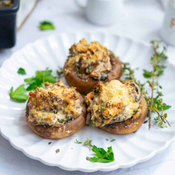Close up of stuffed mushrooms served on a white plate.