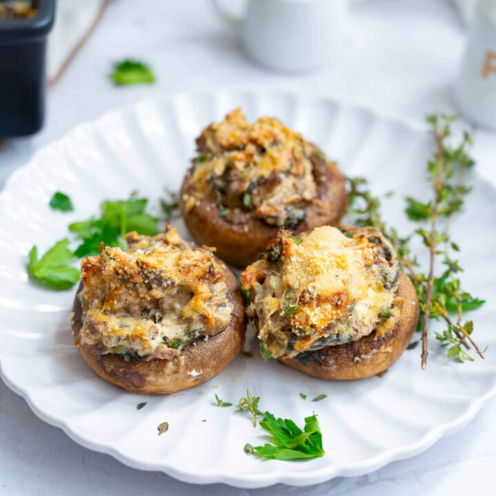 Close up of stuffed mushrooms served on a white plate.