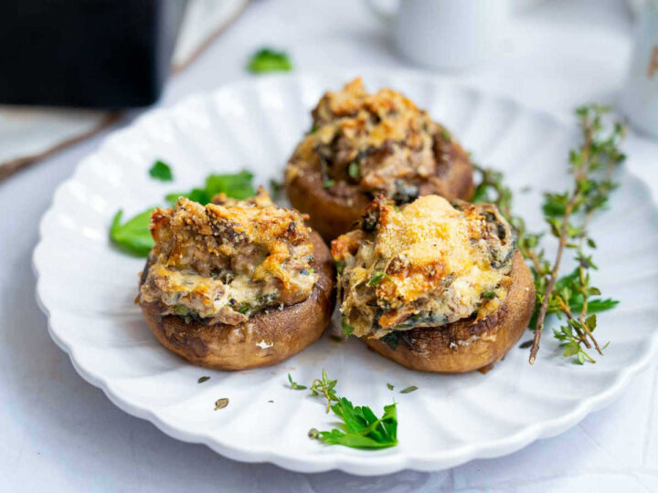 Close up of stuffed mushrooms placed on a white serving plate.