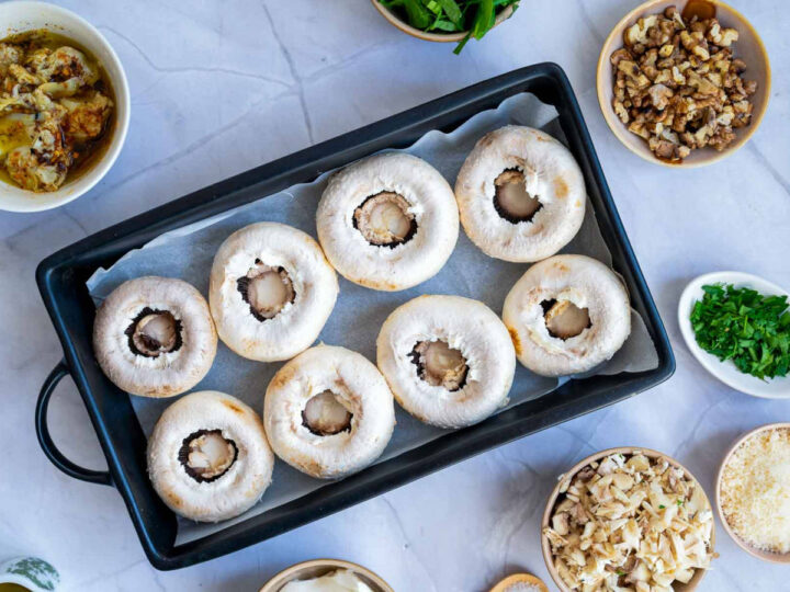 Cleaned mushrooms placed on the baking tray with filling ingredients nearby.