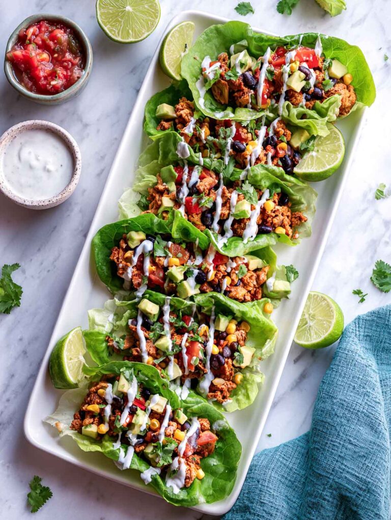 Top-down view of Tex-Mex lettuce cups on rectangular platter with lime and salsa.
