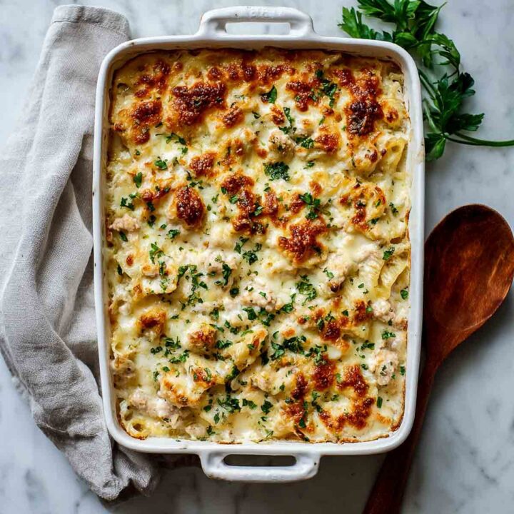 Turkey Alfredo pasta bake with a golden-brown cheesy crust in a white casserole dish.