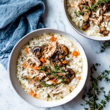 Creamy turkey rice soup in two bowls with mushrooms and thyme.