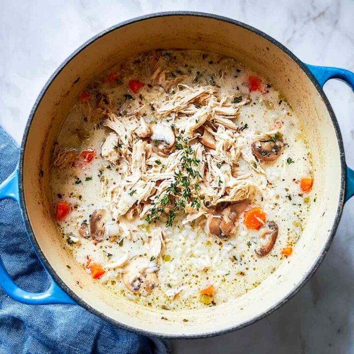 Shredded turkey added to creamy rice soup base in Dutch oven.