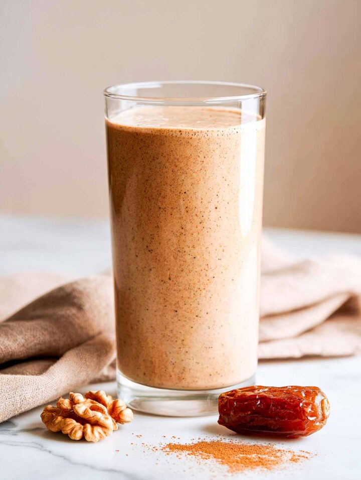 Side view of banana date smoothie in tall glass.