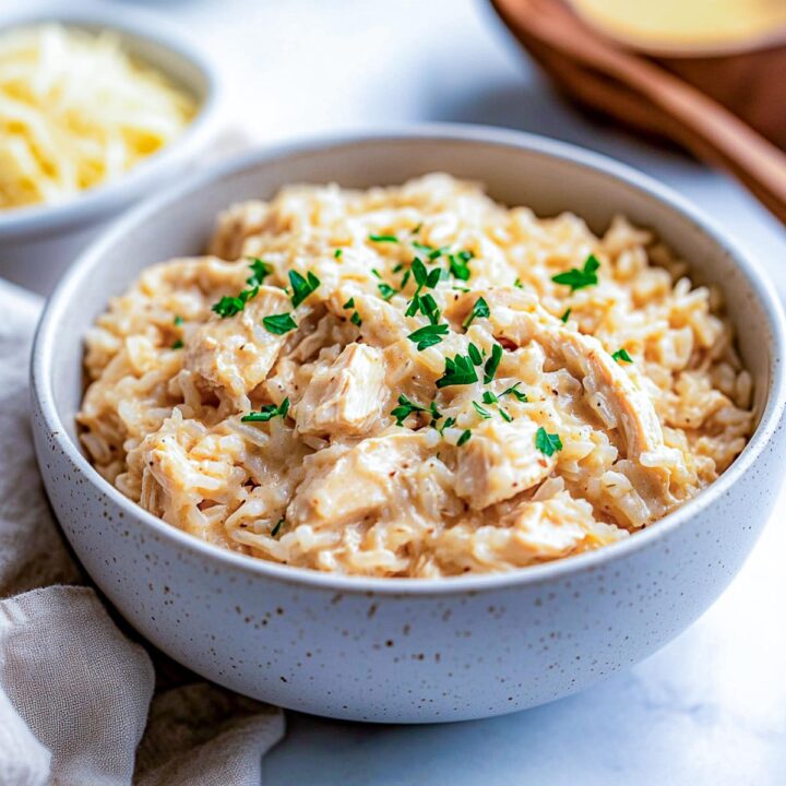 A bowl of chicken and rice made in crockpot on a white marble surface.
