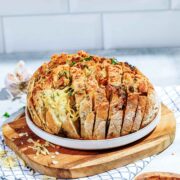 Side view of a round loaf of garlic pull-apart bread placed on a wooden board.