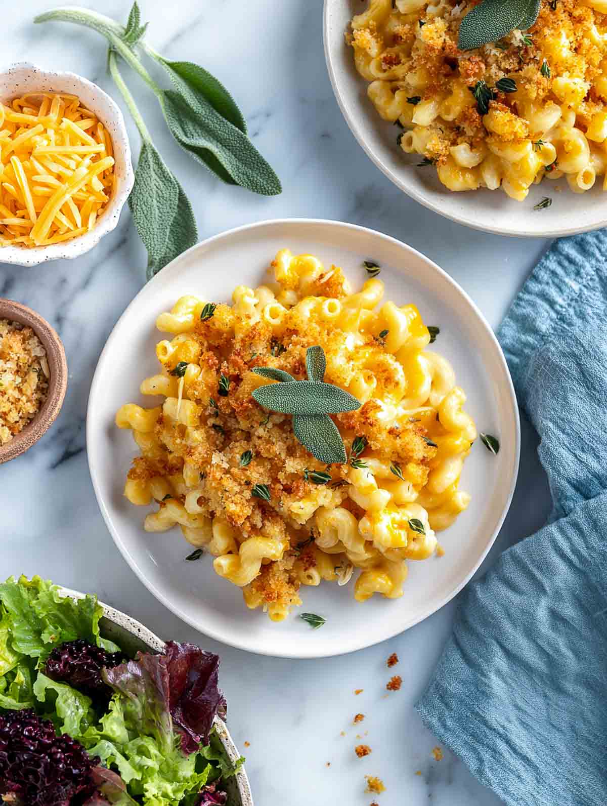 Plated servings of pumpkin sage mac and cheese with crunchy breadcrumb topping.