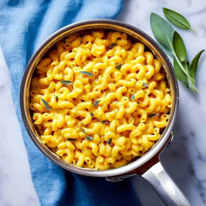 Cooked elbow macaroni coated in creamy pumpkin cheese sauce in saucepan.