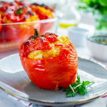 Chicken and rice stuffed red bell pepper baked until tender, served on a plate with a parsley garnish.