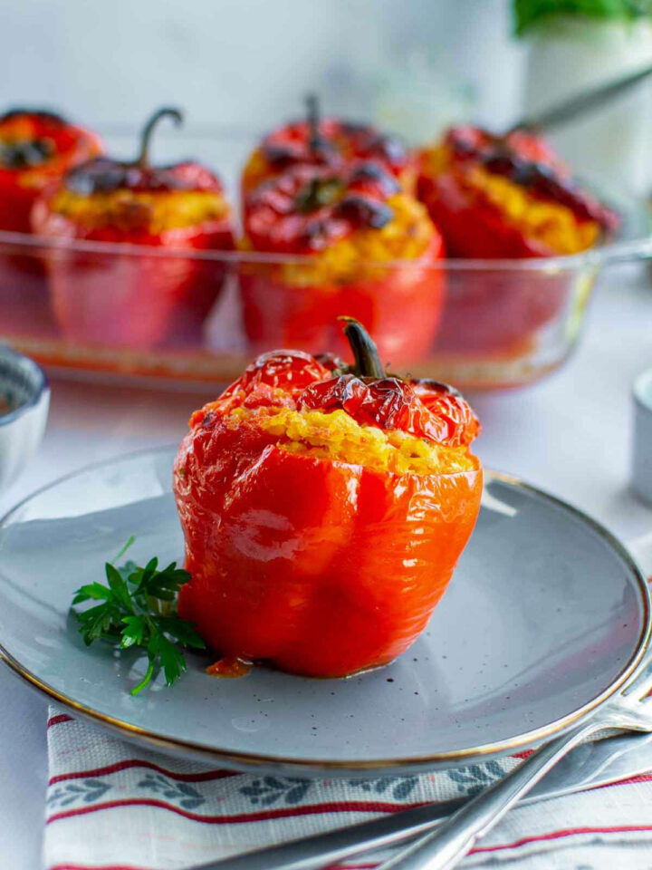 Chicken and rice stuffed red bell pepper served on a plate, with more baked stuffed peppers visible in the background.