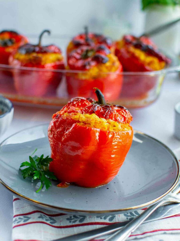 Chicken and rice stuffed red bell pepper served on a plate, with more baked stuffed peppers visible in the background.