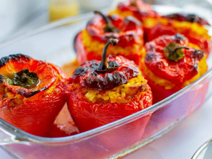 Side view of baked stuffed peppers in a glass baking dish.