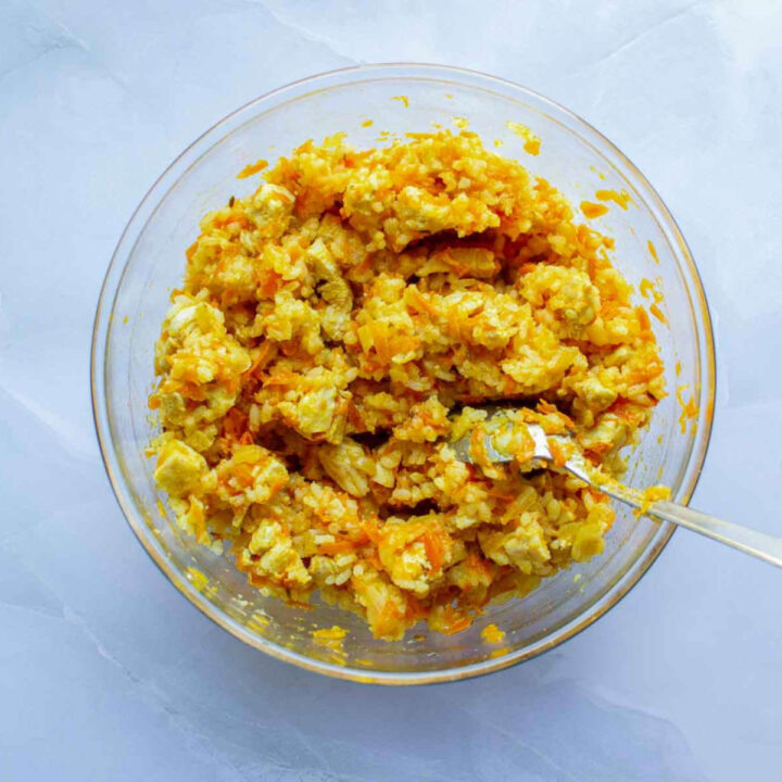 Chicken and rice mixture combined in a glass bowl, showing a thick, golden filling with carrots and onions, ready for stuffing peppers.
