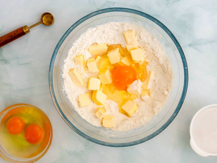 Eggs and cubed butter added to a bowl of dry coconut cake ingredients.